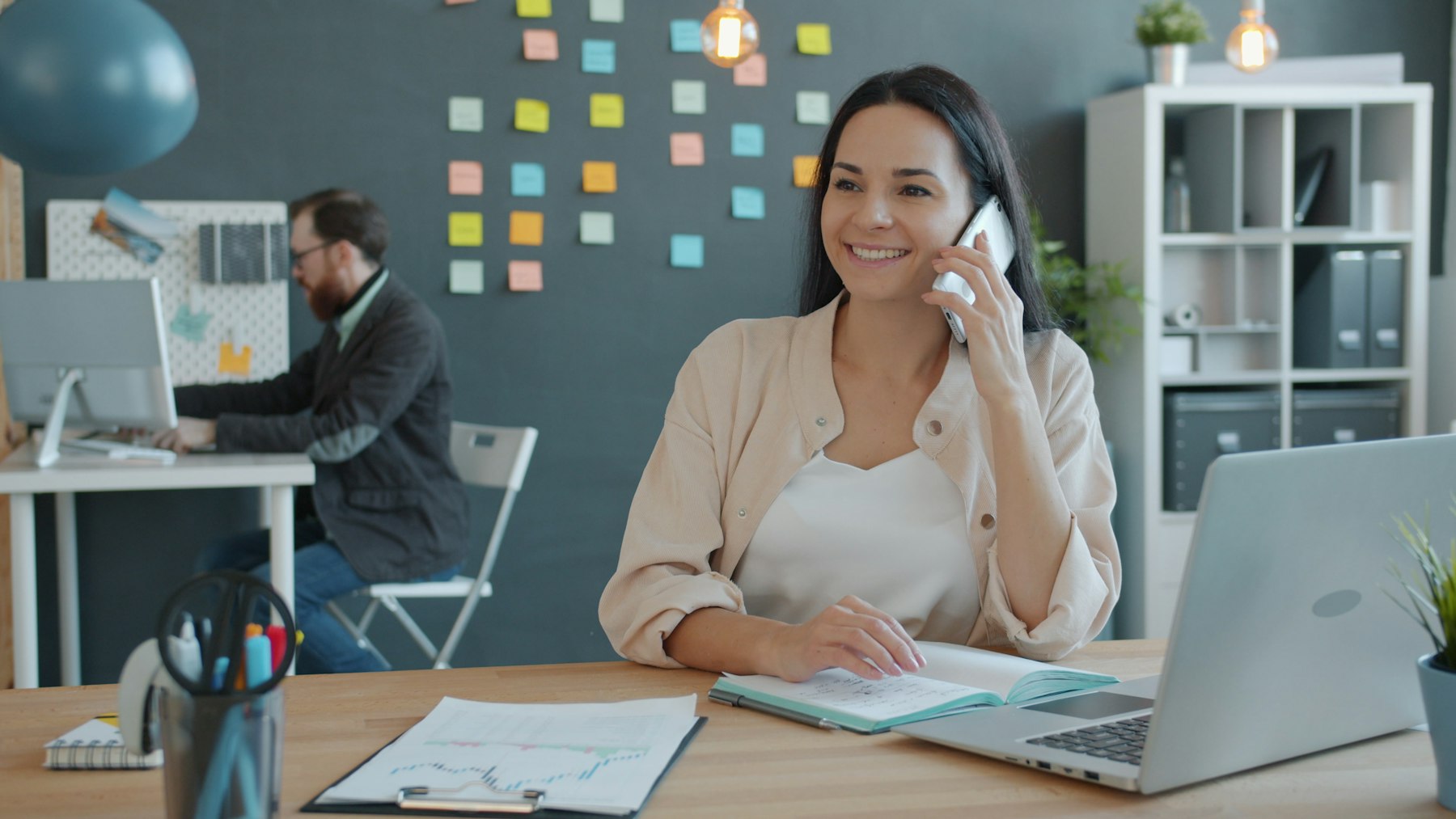 A woman smiling during a phone call at her desk