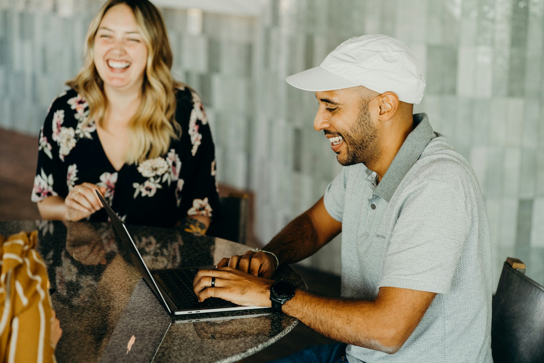 Two colleagues laughing together at a laptop