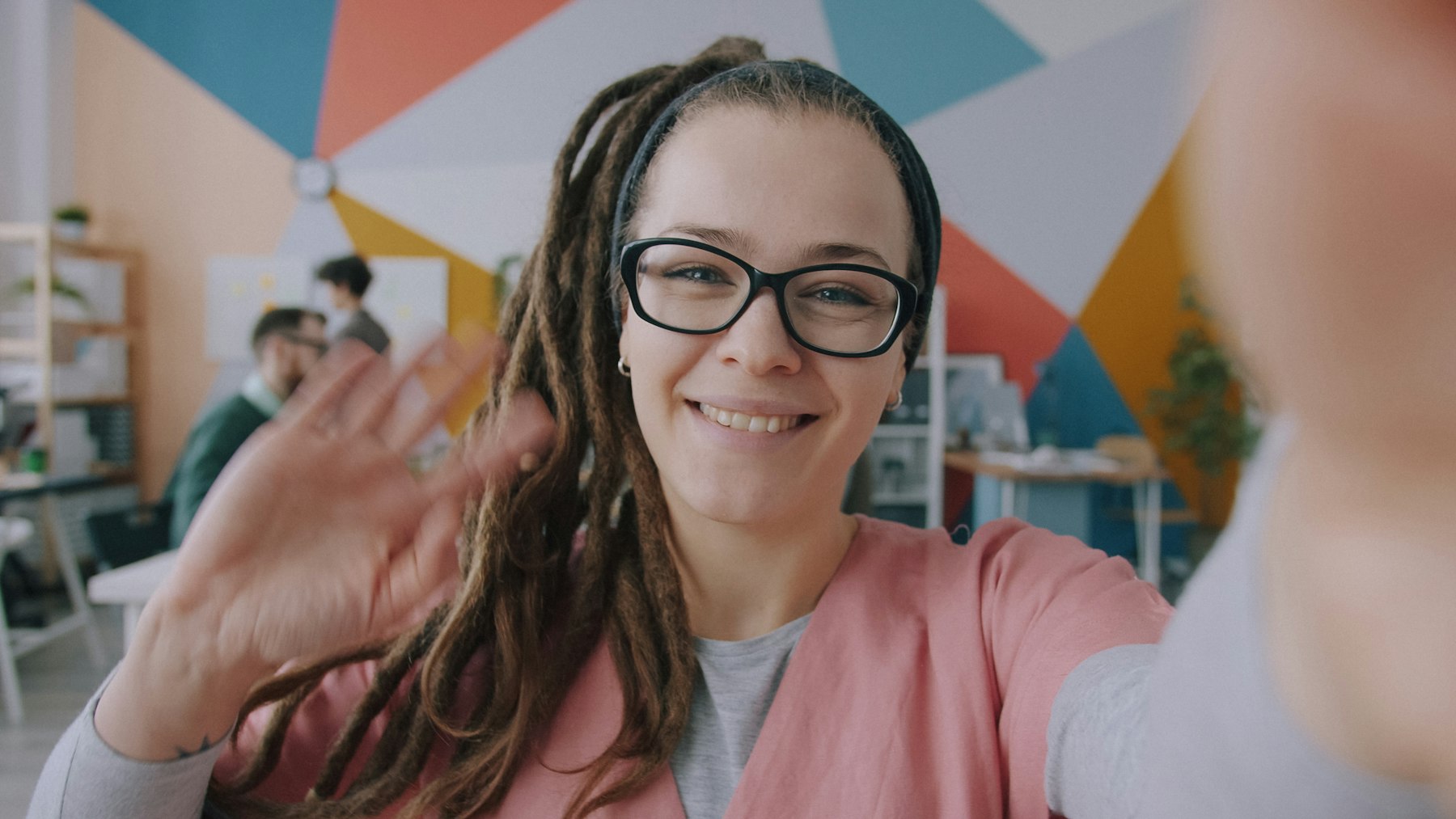A smiling woman waving on a video call